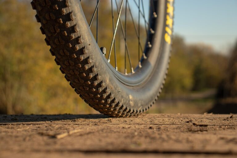 Porównanie trzech różnych opon rowerowych: szeroka opona górska (MTB) z agresywnym bieżnikiem, wąska opona szosowa typu slick oraz opona miejska o średniej szerokości i uniwersalnym bieżniku.